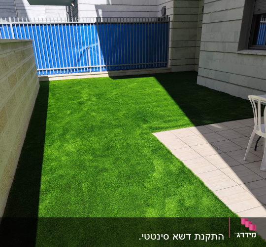 חצר עם דשא סינטטי וכיסאות פלסטיק לבנים